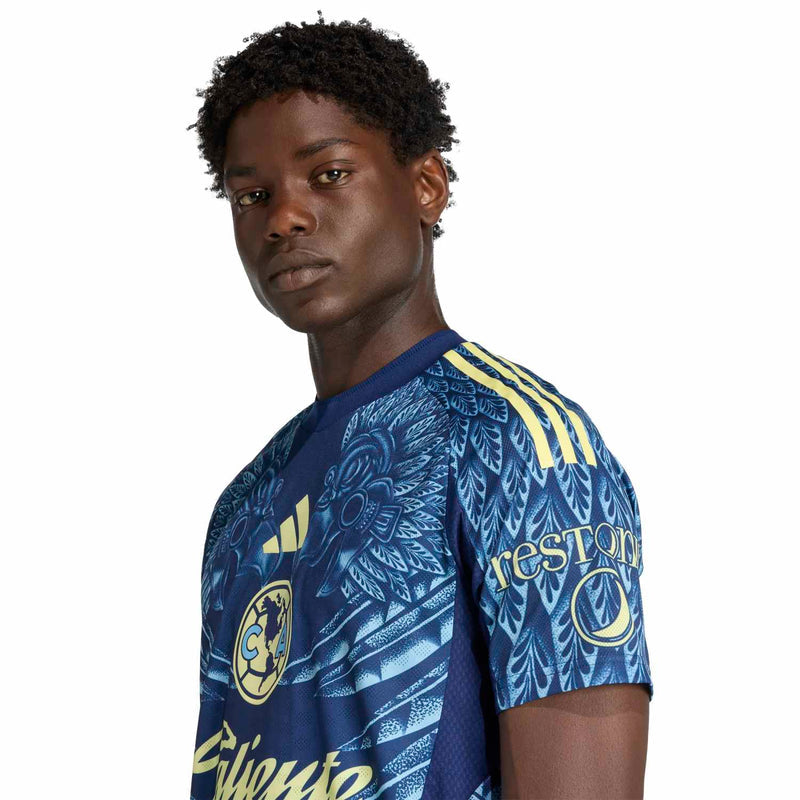 Men's Club America away jersey close-up, navy with leaf pattern and gold trim on shoulder.