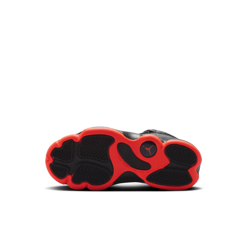 Kids sneaker outsole with red rubber pods and black tread, bottom view