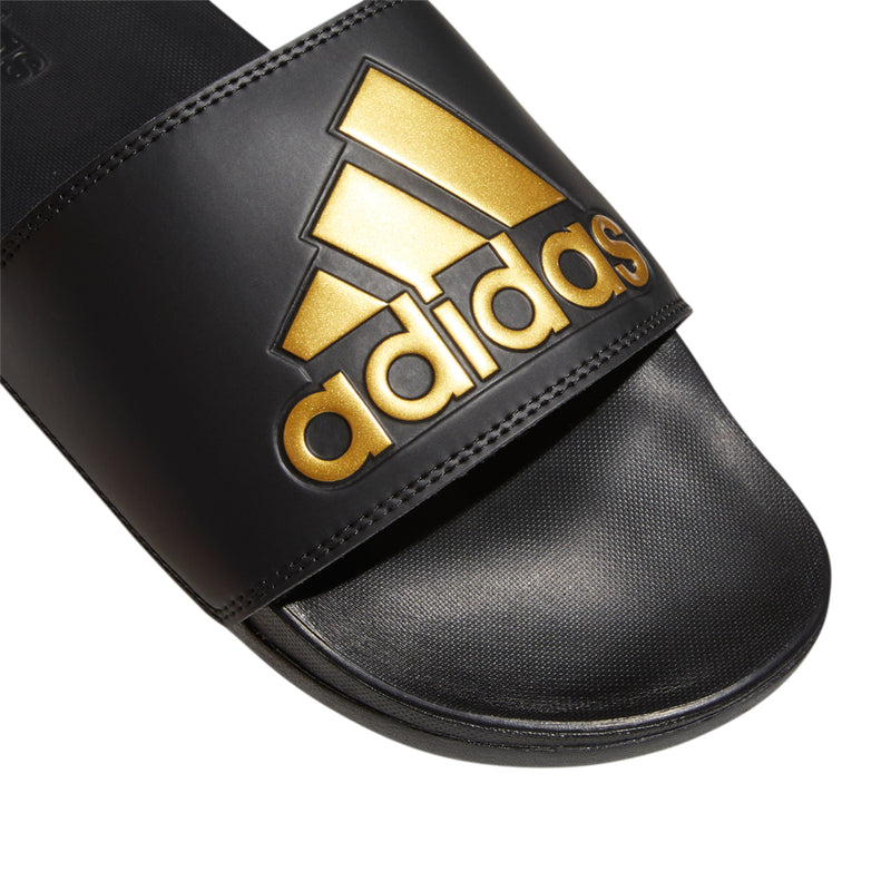 Men's black slide sandals, close-up of gold adidas logo on footbed strap
