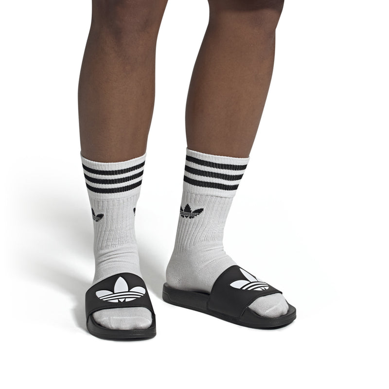 Men's black slide sandals with white socks and black-and-white adidas logo