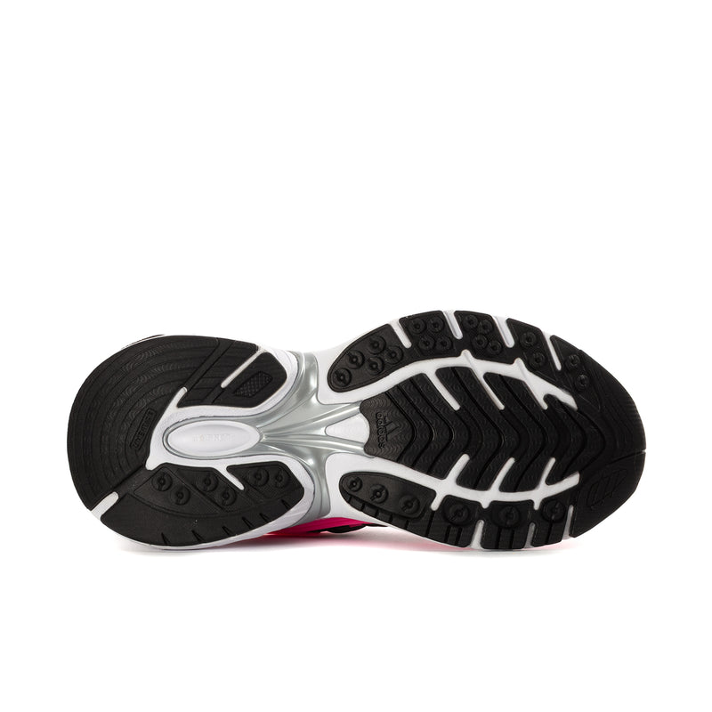 Women's sneaker outsole view, black traction tread with white midsole and hot pink detail