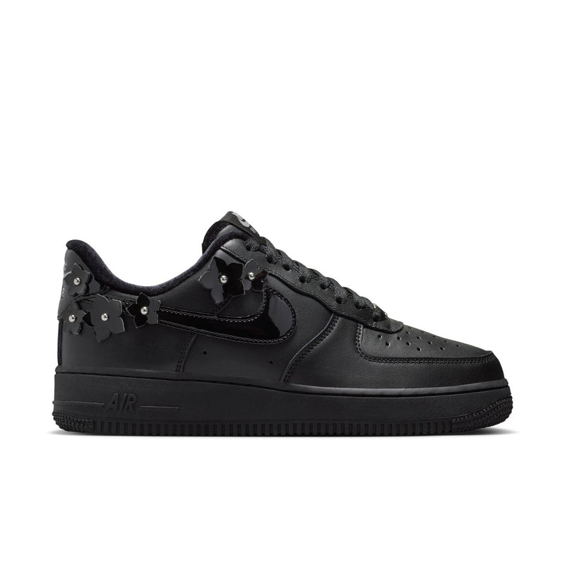 Women's black low-top sneaker with Nike swoosh and lace-up studded charms