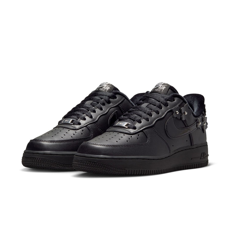 Women's black low-top sneakers, side-by-side view, Nike swoosh and studded charms
