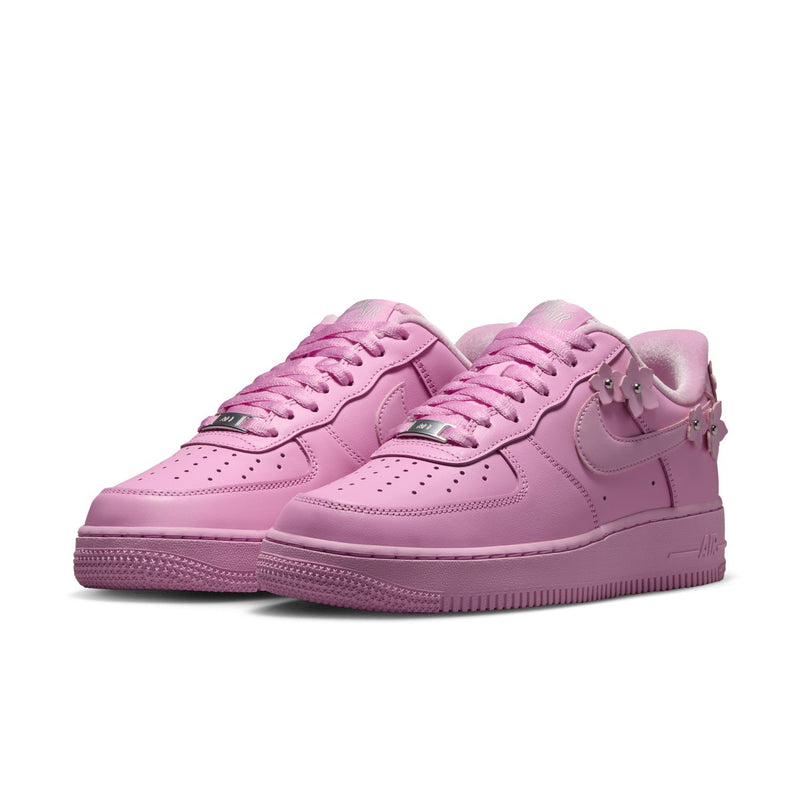 Pair of pink low-top lace-up sneakers with Nike Swoosh and perforated toe