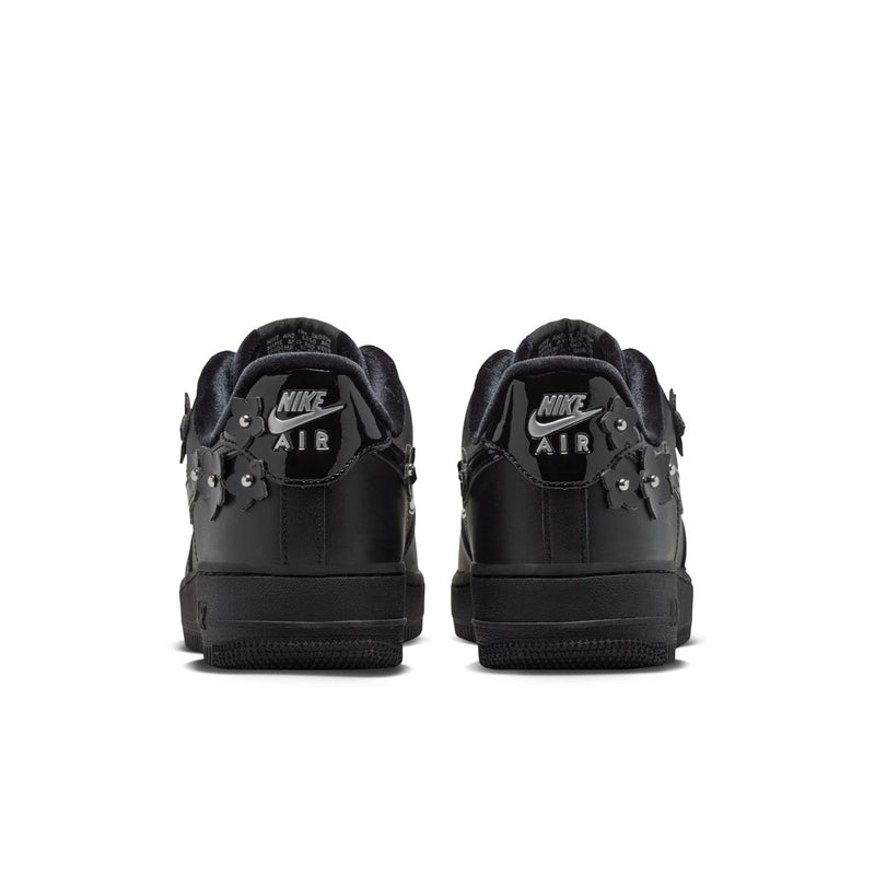 Women's black low-top sneakers, heel view with rear Nike Air branding and charms
