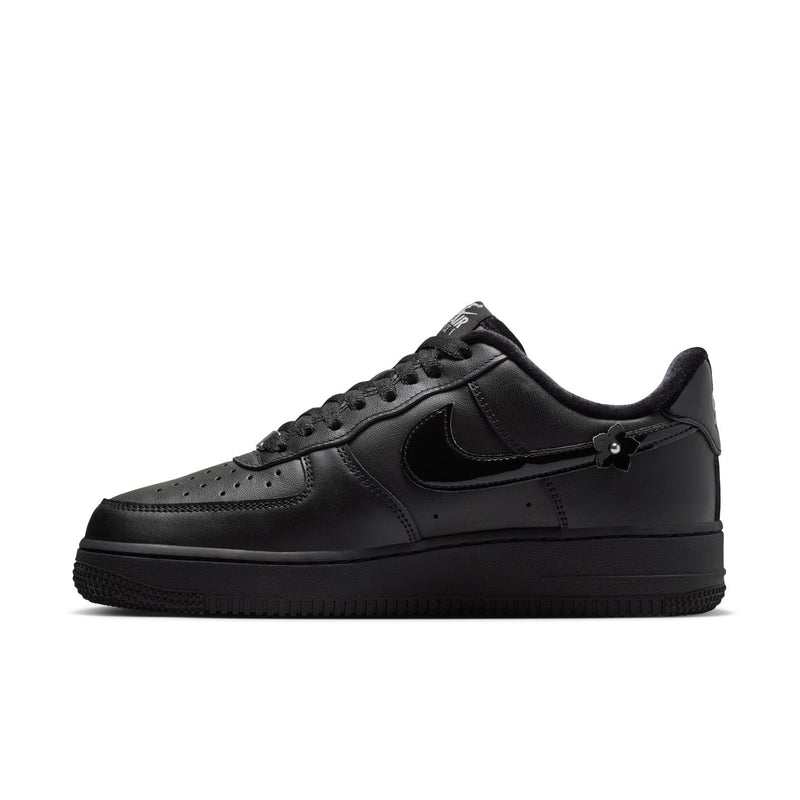 Women's black low-top sneaker, quarter-side view with Nike swoosh and studded appliques