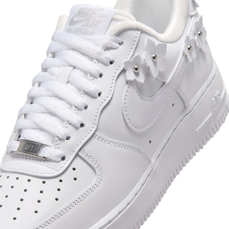 White Nike Air Force 1 tongue and toe box with laces, stitching, and gold lace stay