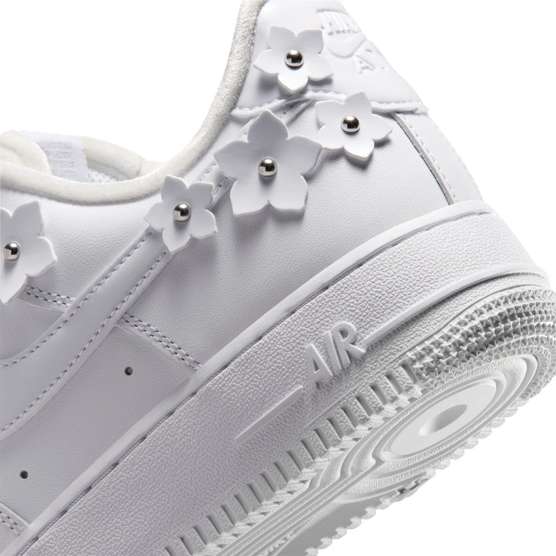 Close-up of white Nike Air Force 1 side with swoosh, metallic studs, and textured sole