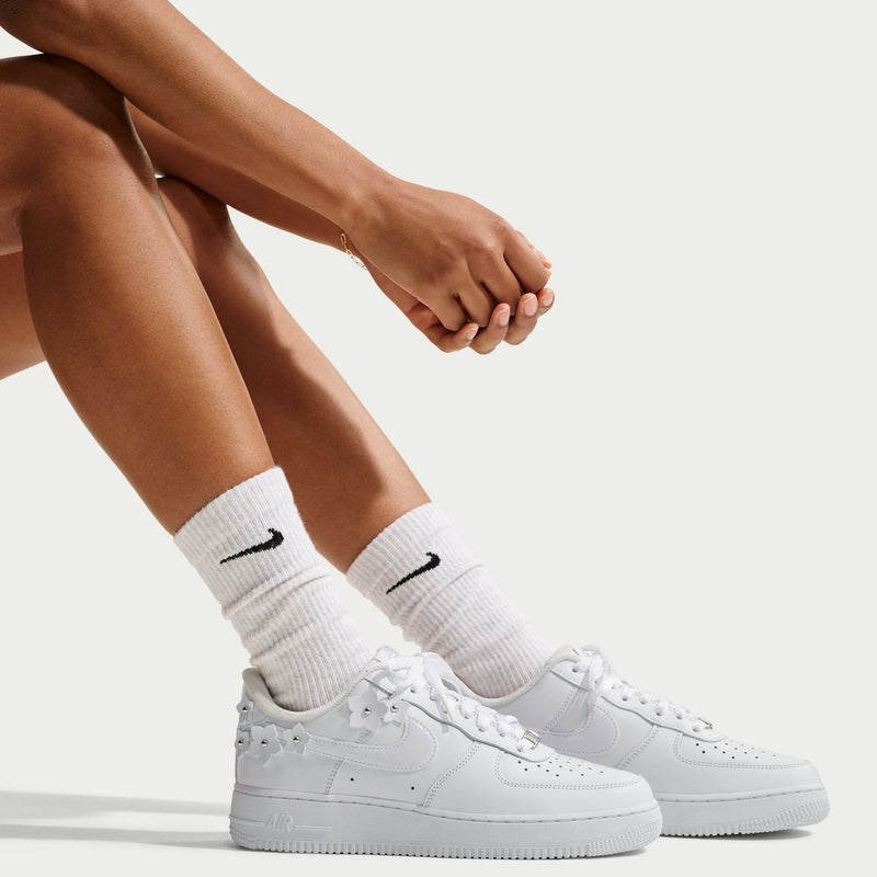 White Nike Air Force 1 sneakers on feet with white socks and lace-up fronts