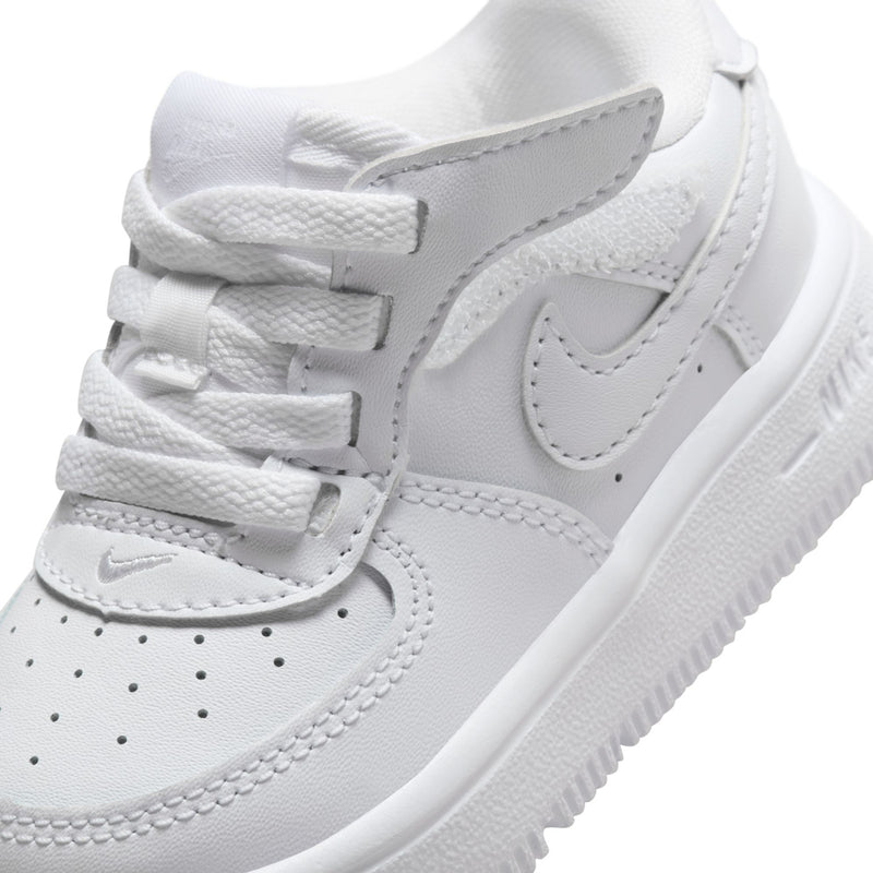 White toddler sneaker close-up with lace-up, stitched swoosh, and grippy sole