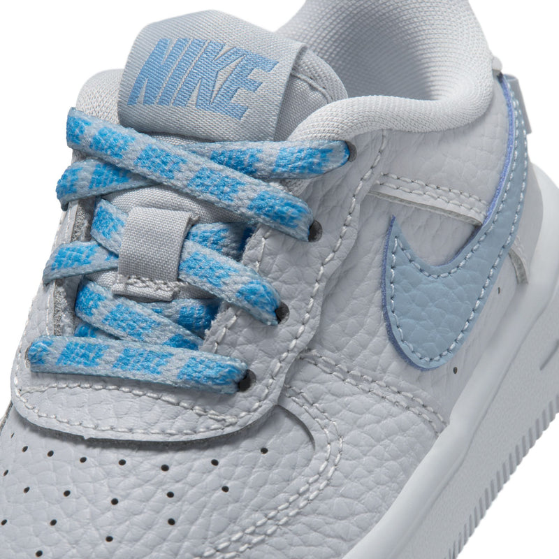 Toddler low-top sneaker close-up, gray leather with blue laces and Nike heel tab