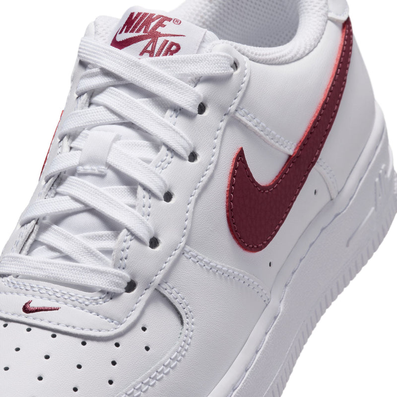 Youth low-top sneakers, close-up of white laces and burgundy Nike Swoosh