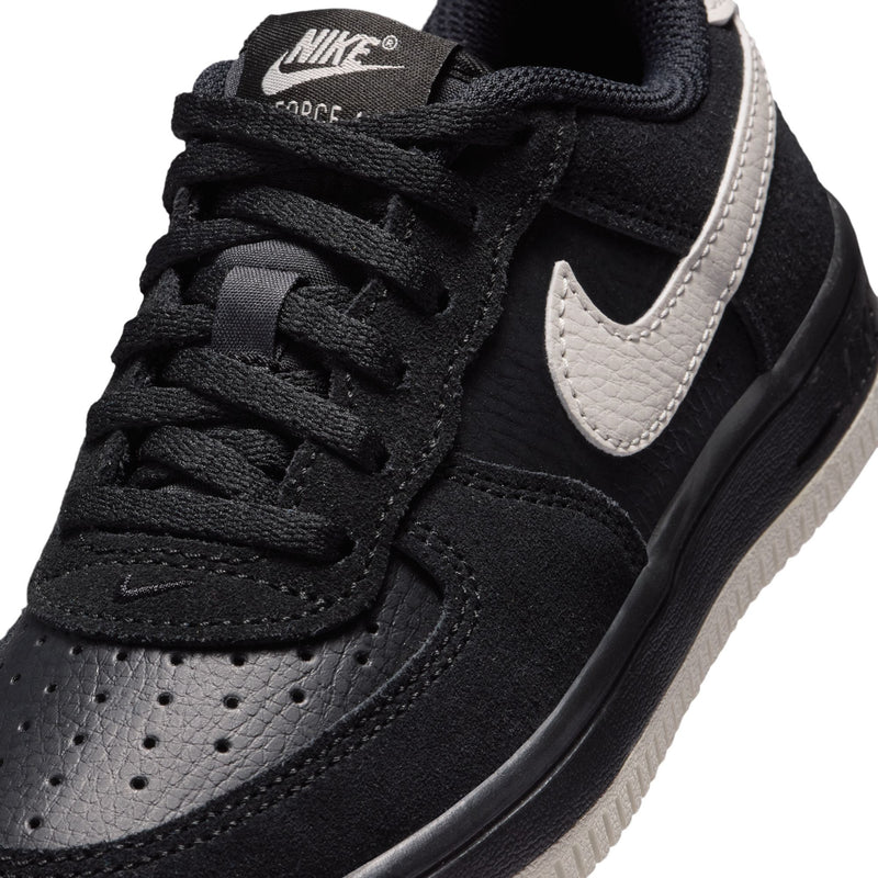 Close-up of kids black lace-up sneakers with light bone swoosh and stitched panels
