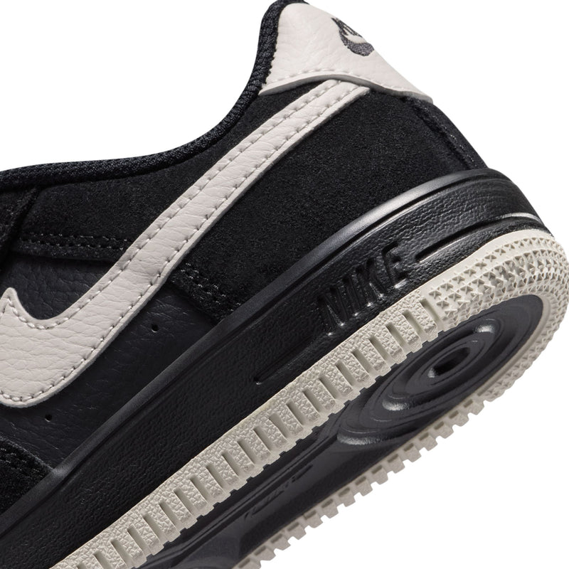 Kids black sneaker side view with light bone stripe and visible Air sole unit
