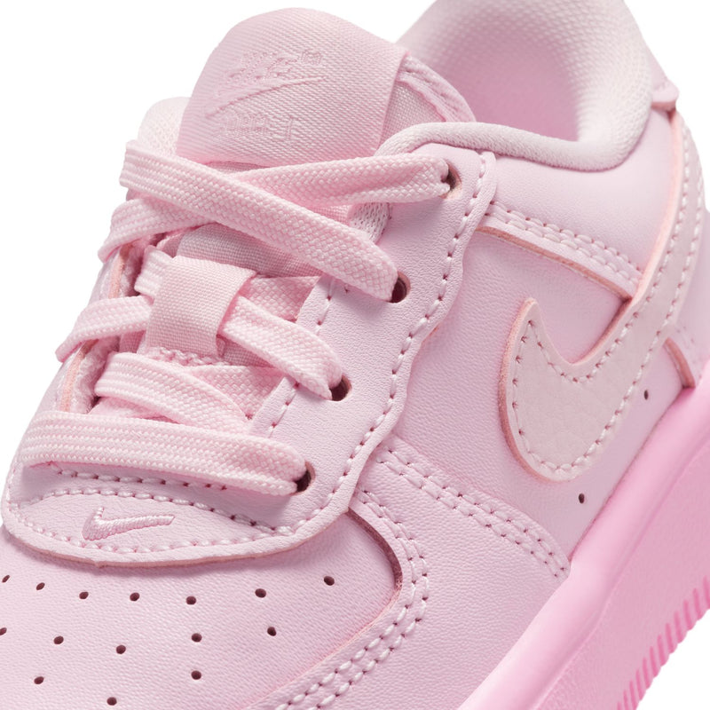 Close-up of pink toddler sneaker: lace, stitching, perforated toe panel, and swoosh