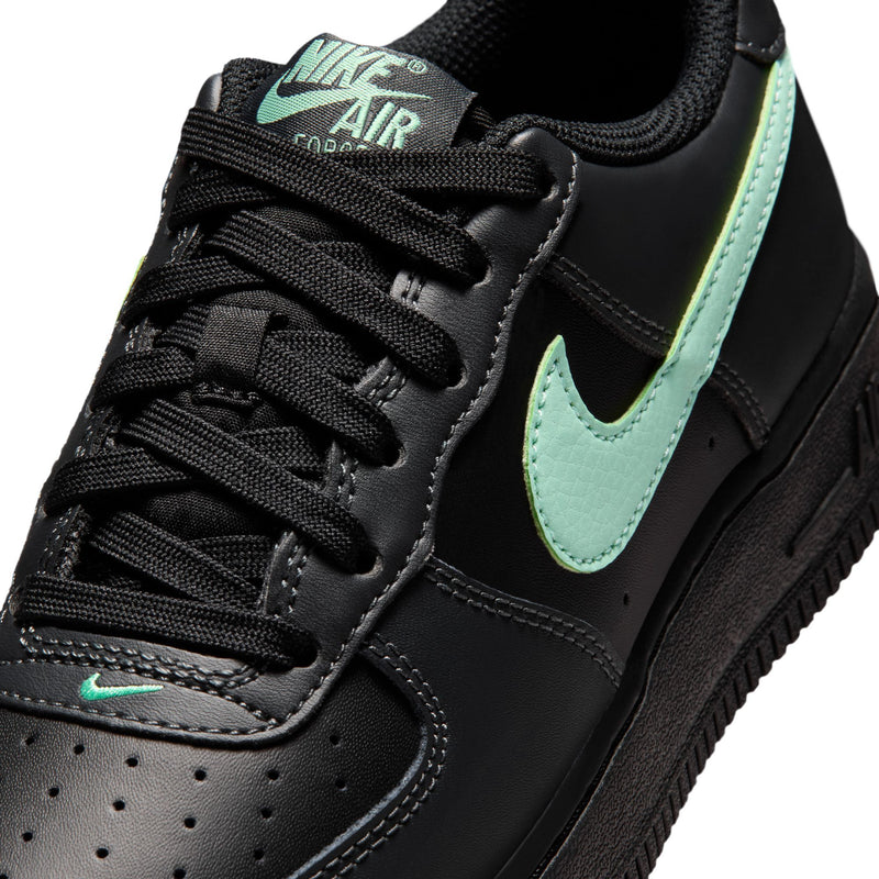Close-up of black youth sneaker upper with mint green Swoosh and black lace stitching.