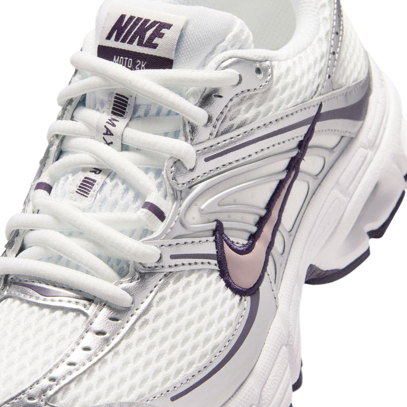Close-up of youth white sneaker with lace-up front, purple accents, and NIKE logo