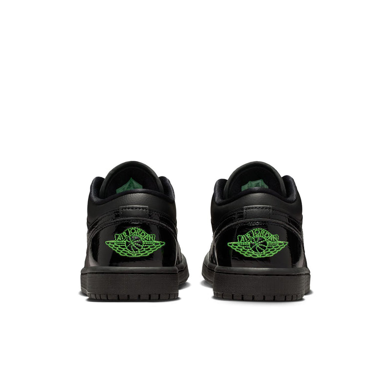 Black low-top sneakers with green heel logos and rubber outsole tread.