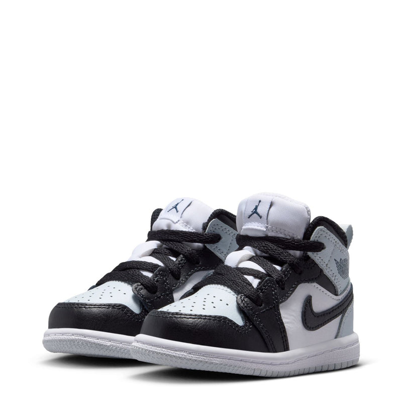 Pair of toddler mid-top sneakers in white and black with perforations and black lace-up closure