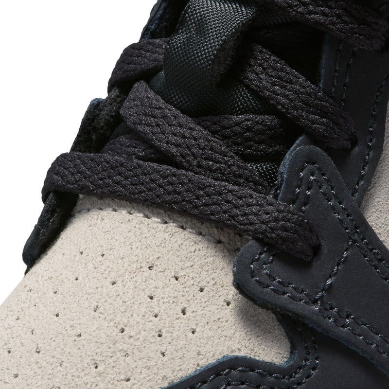 Toddler sneaker close-up, black laces over off-white perforated panel and stitched overlay