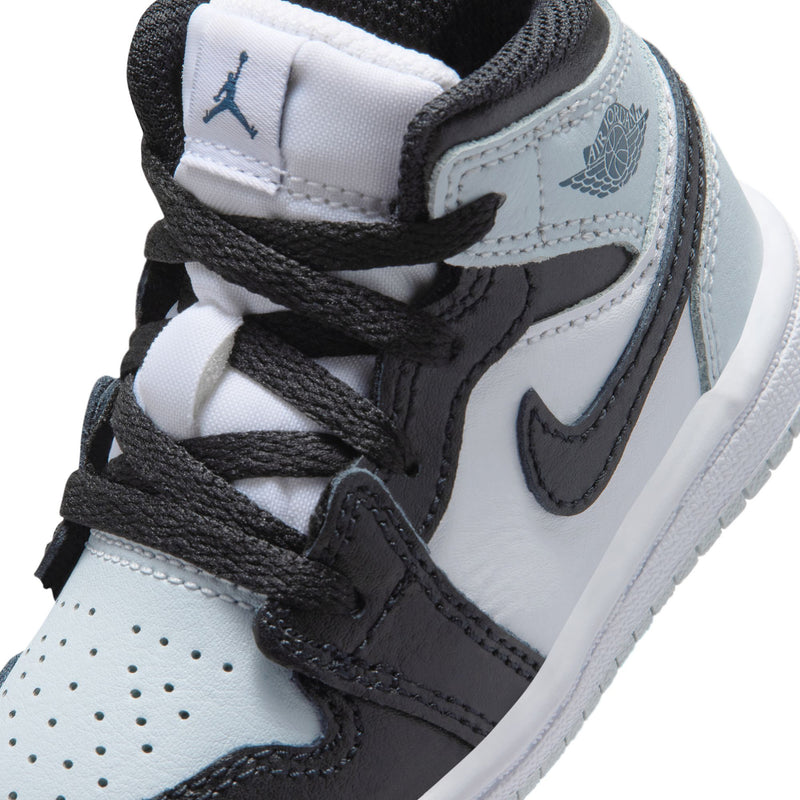 Toddler mid-top sneaker close-up with black laces, swoosh, stitched overlays, and logo on tongue