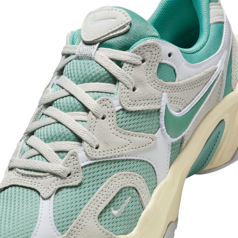 Women's sneakers close-up: teal mesh, light gray overlays, and lace-up front