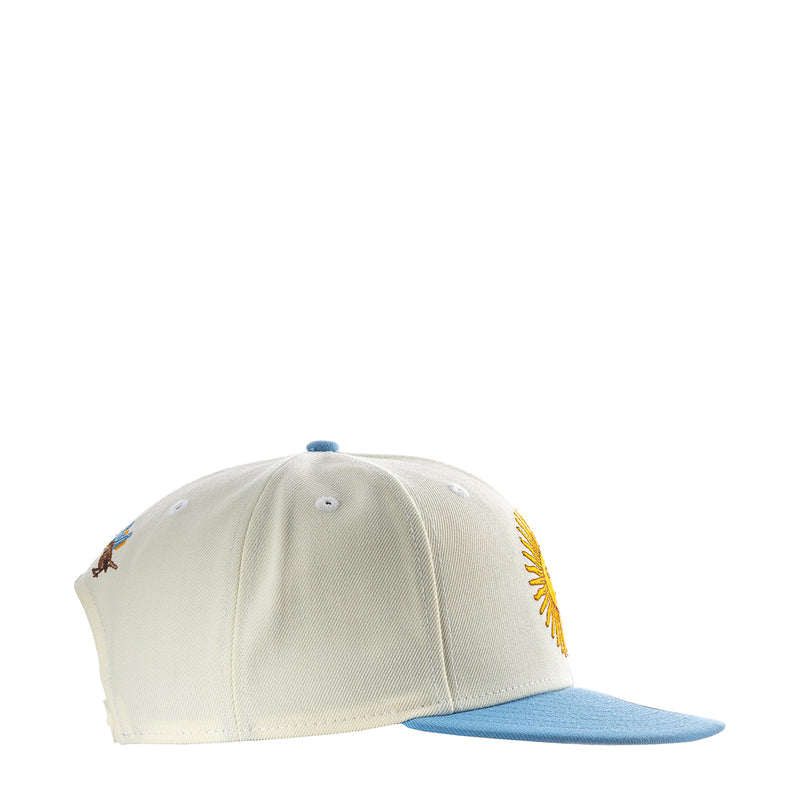 Cream baseball cap with embroidered side graphic and light blue brim