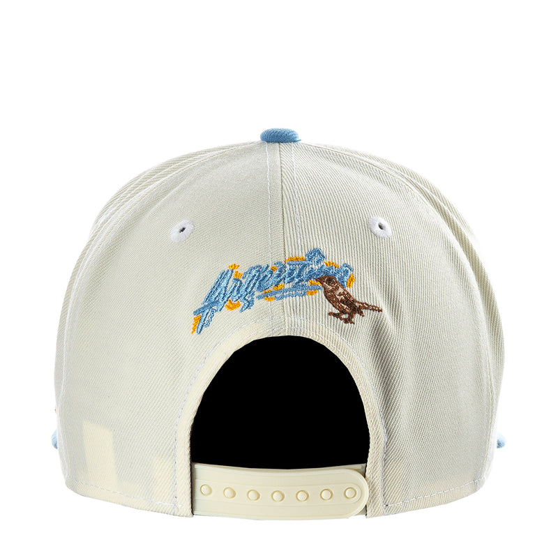 Cream baseball cap with back embroidered scene and light blue brim