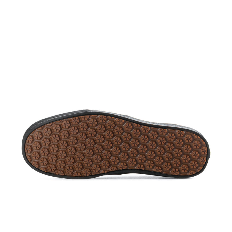 Gum-brown treaded outsole of men's black canvas sneakers with grip pattern