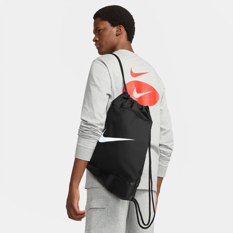 Black drawstring gym sack with white swoosh, worn on back