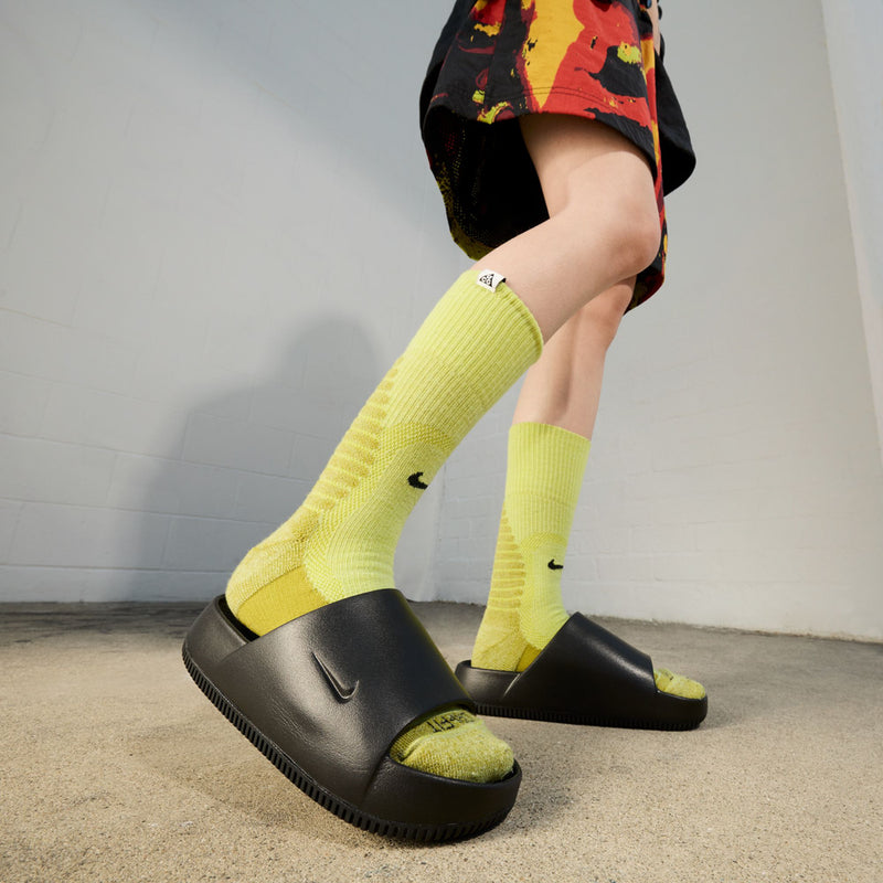 Black slide sandal with neon-yellow socks in a sporty side view