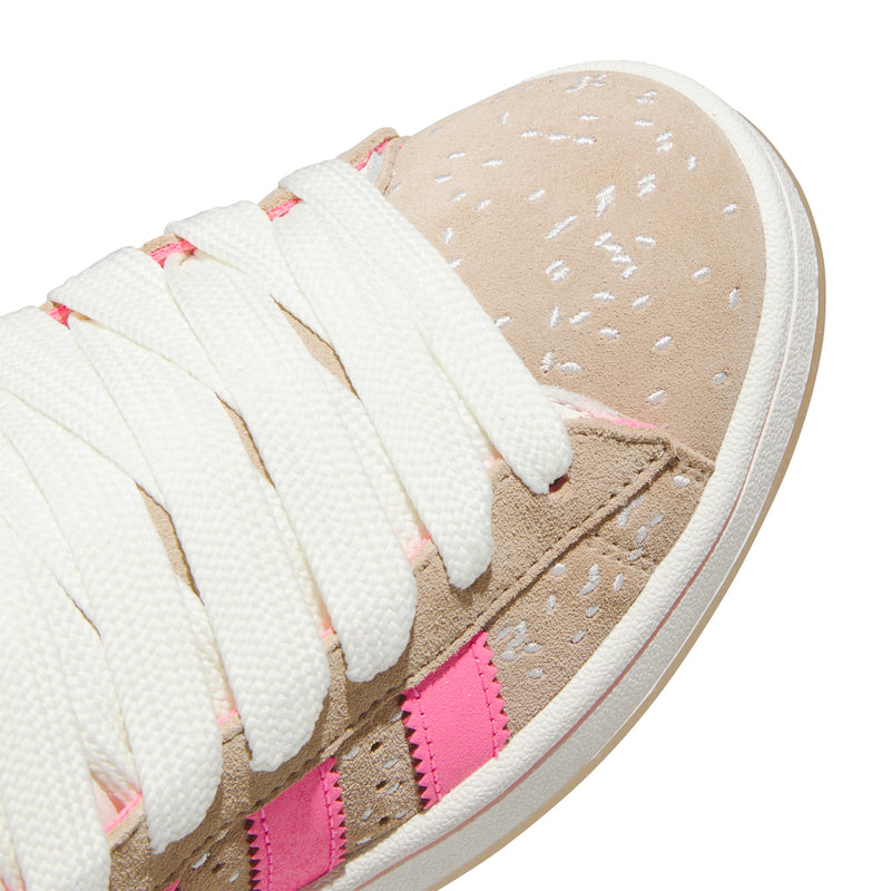Women's sneakers side close-up, tan suede speckle texture with pink stripe