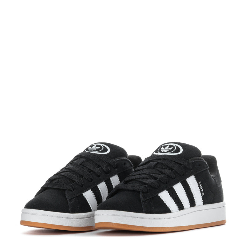 Pair of youth black low-top sneakers with white stripes and gum soles