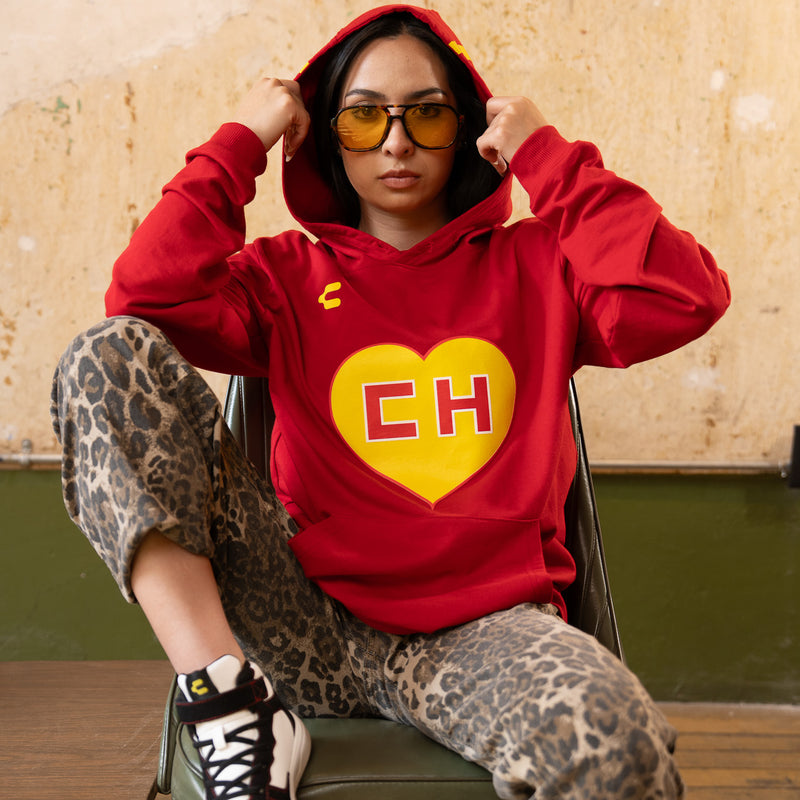 Red pullover hoodie on model with hood up and yellow CH heart graphic
