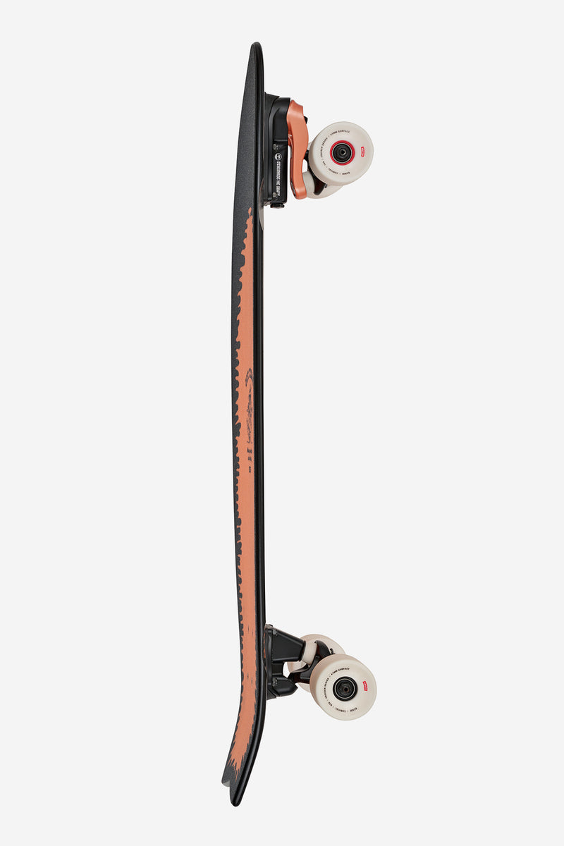 Side profile of Chromantic 33 Lightning Log surf skate with black deck edge orange graphic and white wheels