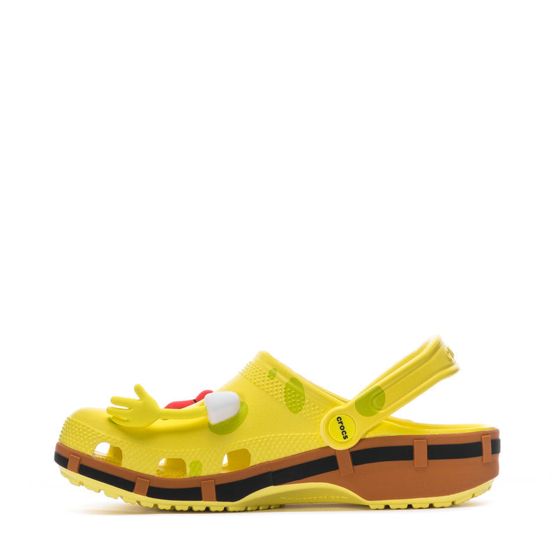 Men's yellow clog side view with cartoon charms, white toe accents, black and orange sole