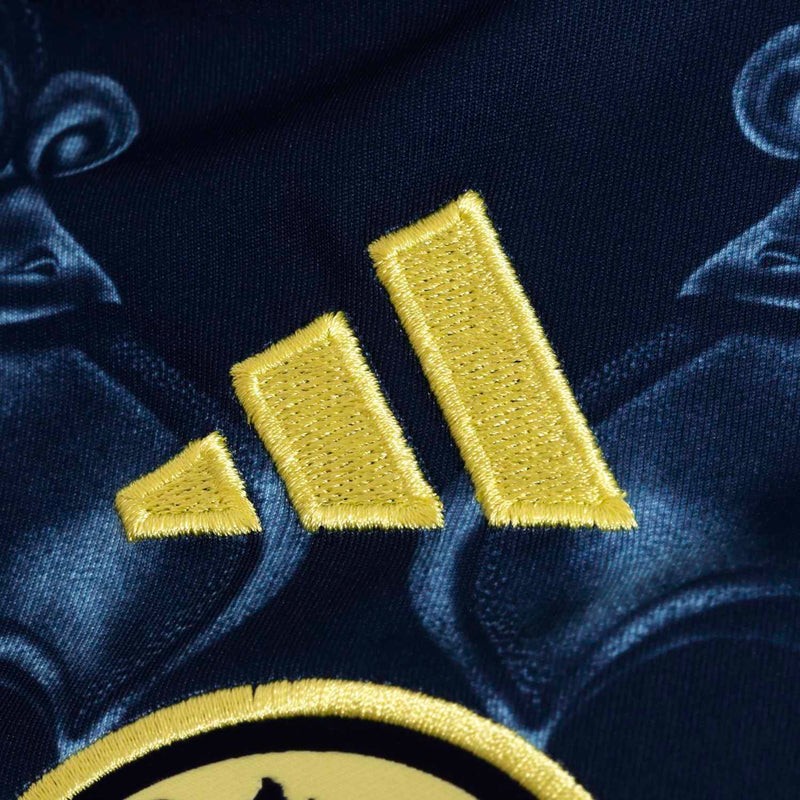 Youth Club America away jersey, close-up of gold embroidered logo on navy fabric