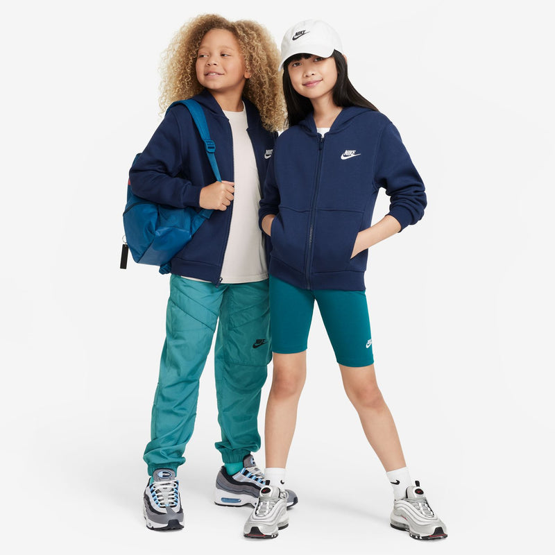 Youth navy zip-up fleece hoodie with hood and Nike chest logo, shown in side profile.
