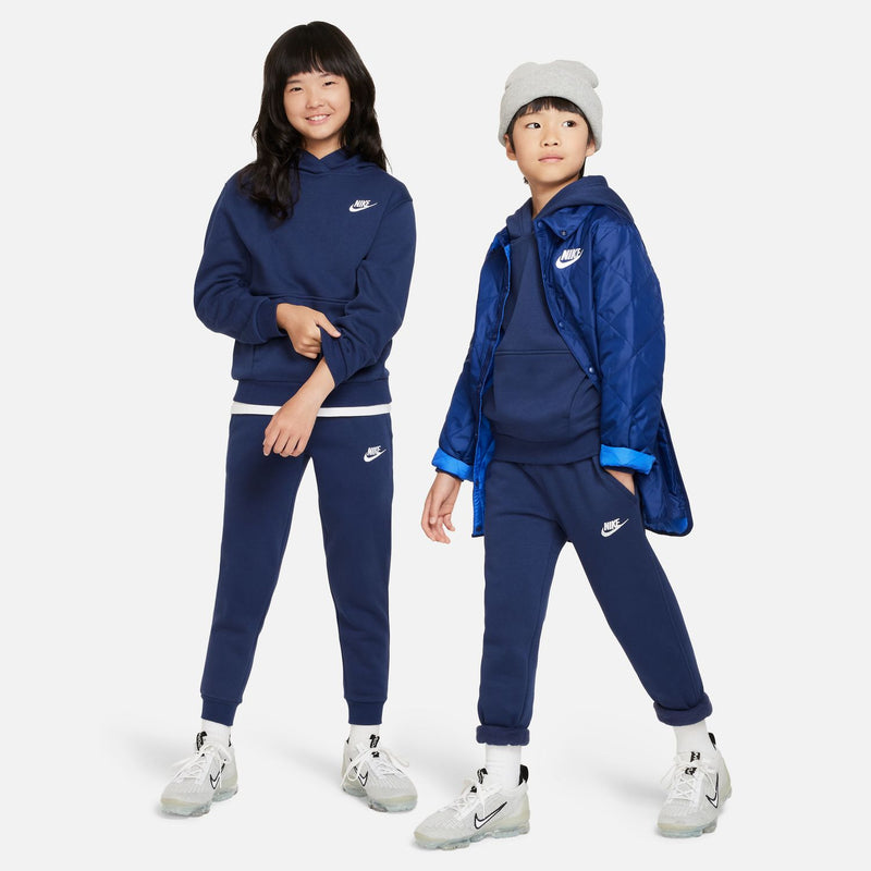 Youth fleece joggers in midnight navy with white Nike logo, worn by two kids.
