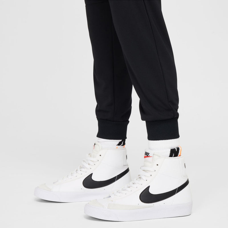 Youth black jogger pants with ribbed ankle cuffs and white sneakers
