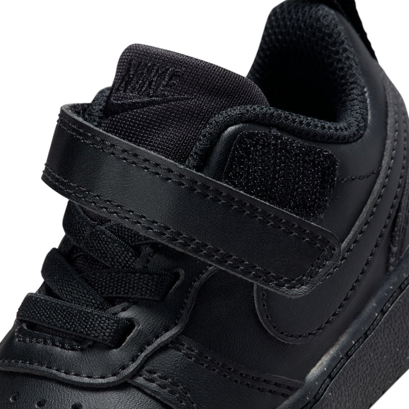 Black toddler sneaker close-up of hook-and-loop strap, Nike Swoosh, and laces
