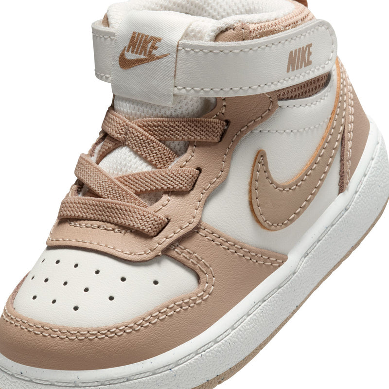 Toddler mid-top sneaker close-up, tan Nike swoosh on pale ivory