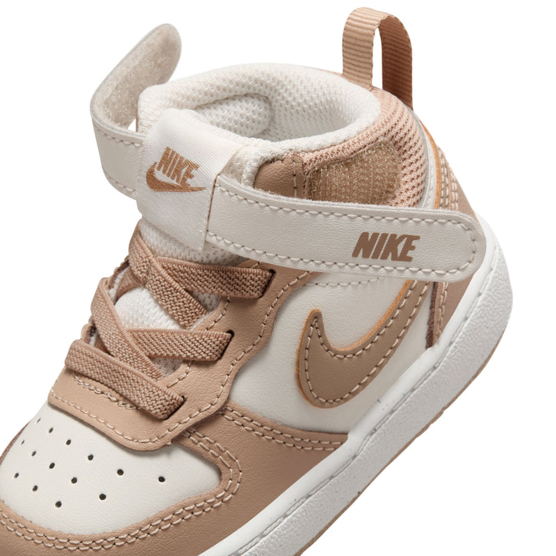 Toddler sneaker close-up, padded collar and tan Nike swoosh on pale ivory