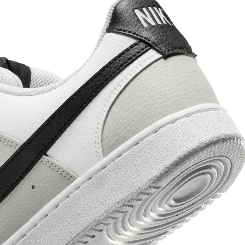 Close-up of low-top men's sneaker heel in white leather with black stripe and Nike tab.