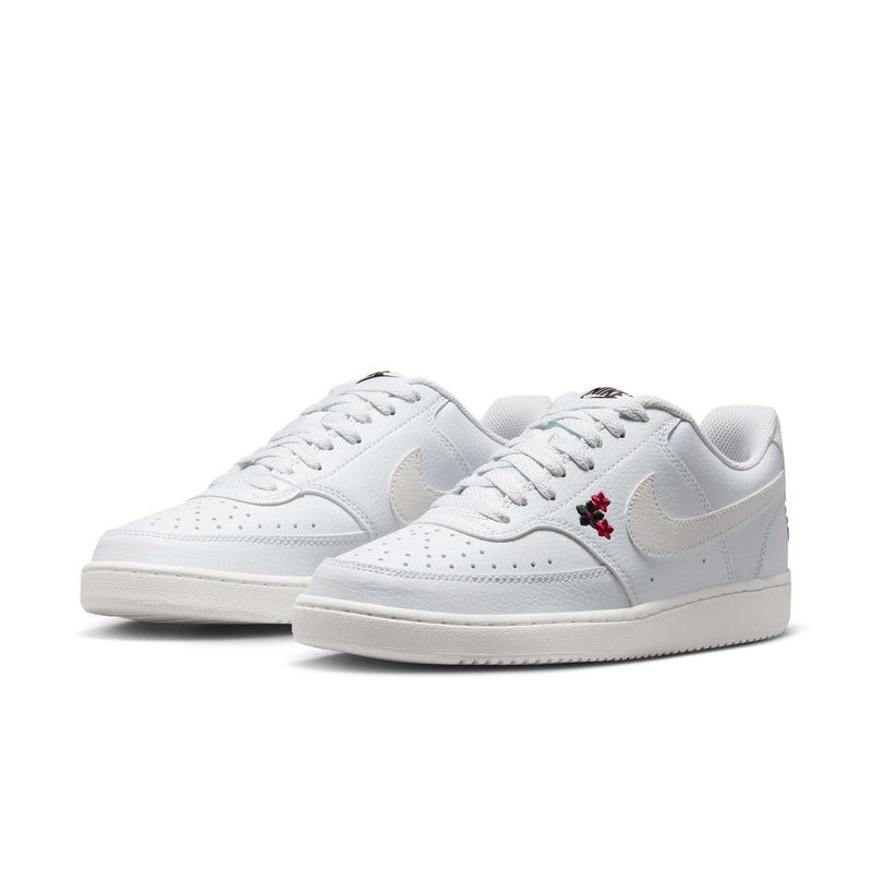 Pair of off-white low-top sneakers with white laces, Nike swoosh, and red flower detail