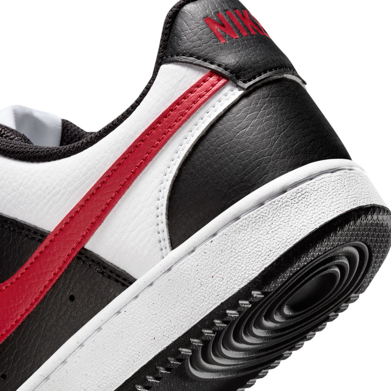 Women's sneaker side close-up: black leather, white panel, red stripe, Nike heel tag.