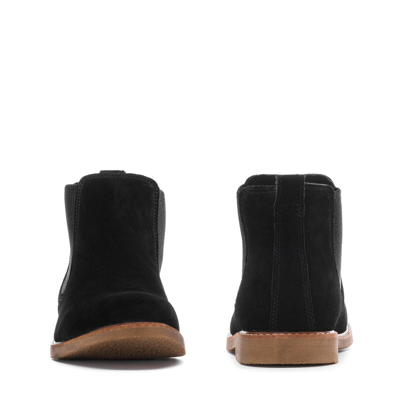 Black chelsea boots with elastic sides and tan rubber sole