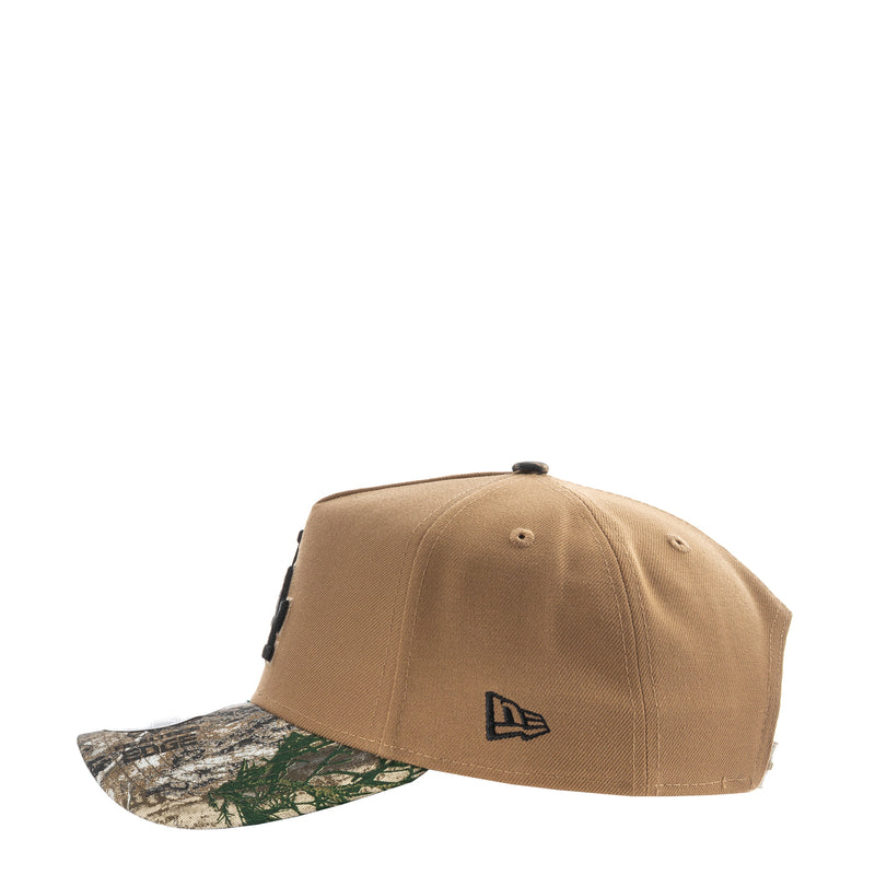 Tan baseball cap with New Era flag logo on side and camo-pattern brim