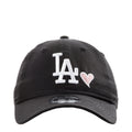 Black baseball cap with white LA logo and pink heart detail on front