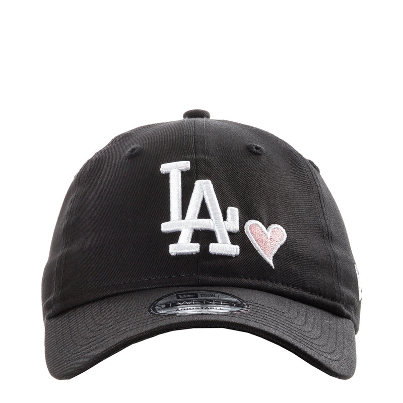 Black baseball cap with white LA logo and pink heart detail on front